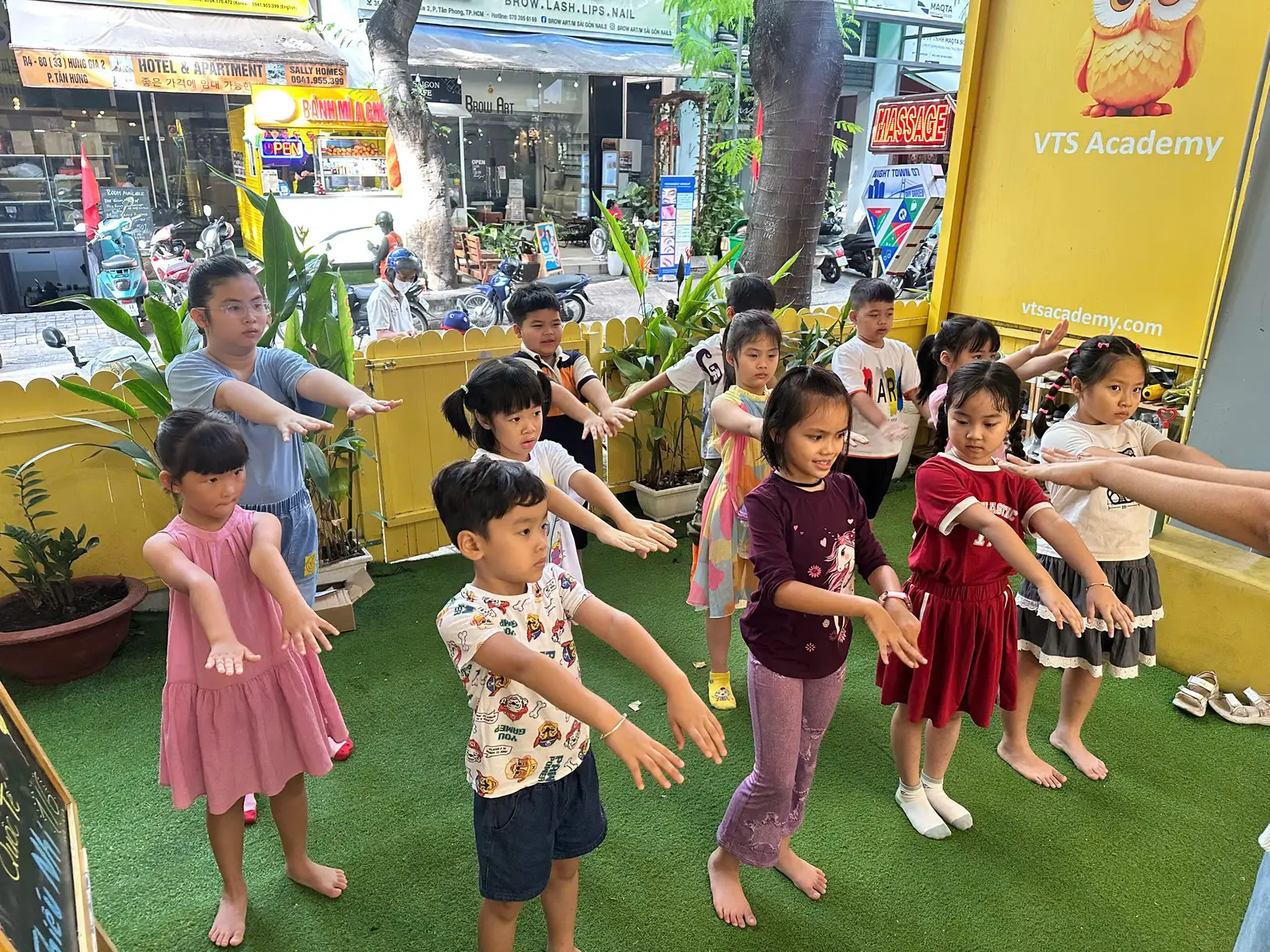 Một buổi tập thể dục buổi sáng tại sân chơi của trường VTS Academy, các bạn nhỏ đang cùng nhau thực hiện các động tác khởi động dưới sự hướng dẫn của cô giáo.